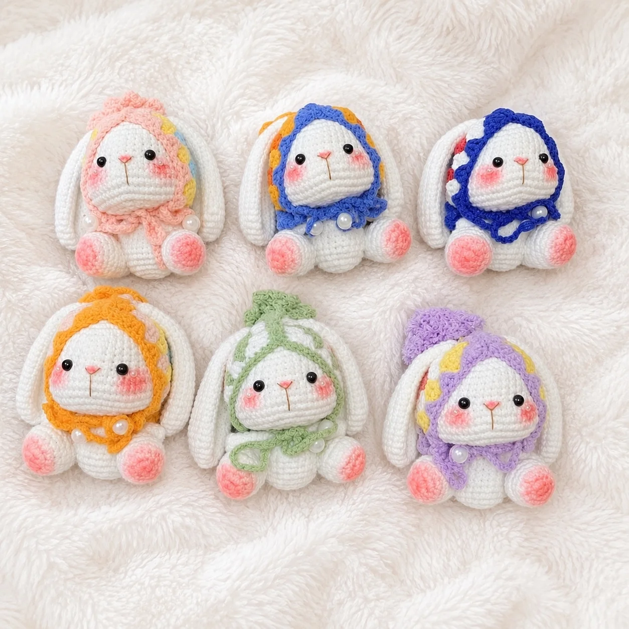 Six handmade bonnet bunnies in different colours, gathered together on a cream blanket